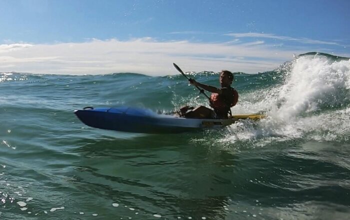 Daniele Giannatempo riding a wave on a Viking Espri kayak, viewed from the side