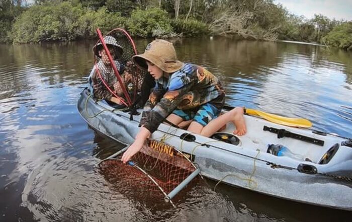 Kids collecting crabs from a Viking Espri kayak in a quiet river setting