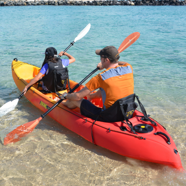 Family launching a double kayak from the beach for a self-pickup rental adventure.