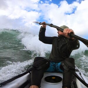 Man paddling hard through beach surf with splash