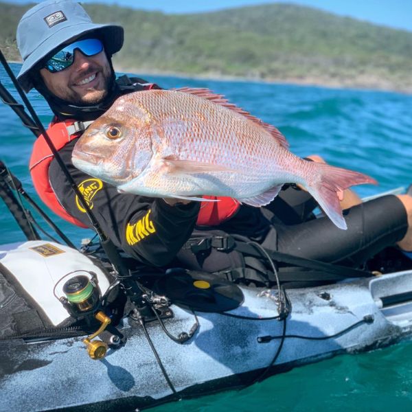 Man holding a large fish on a viking fishing kayak