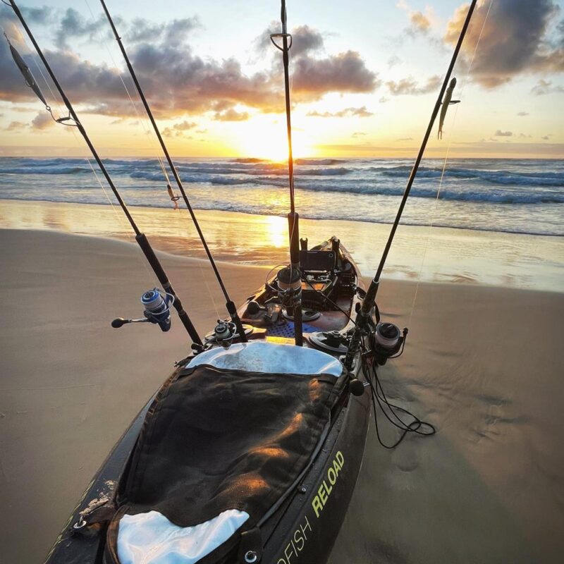 Viking Profish Reload fishing kayak loaded with rods on the beach at sunrise, ready for offshore launch.