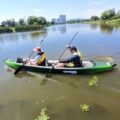 Two adults paddling the Odyssey Tandem inflatable kayak on a calm lake