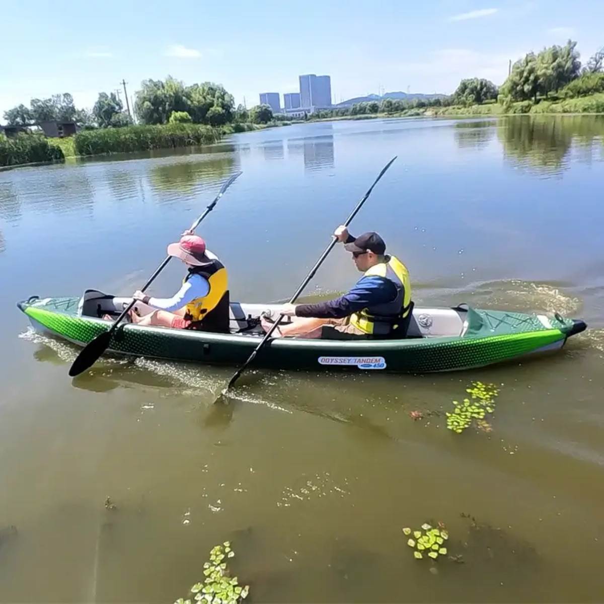 Two adults paddling the Odyssey Tandem inflatable kayak on a calm lake