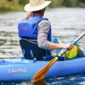 Man paddling a sit-on-top kayak wearing Palm Meander Highback PFD with high-back cut-out design
