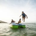 People jumping into the water from a Pelican Monaco DLX pedal boat
