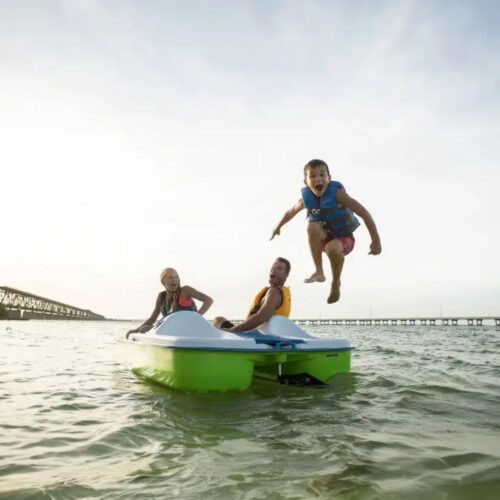 People jumping into the water from a pelican monaco dlx pedal boat