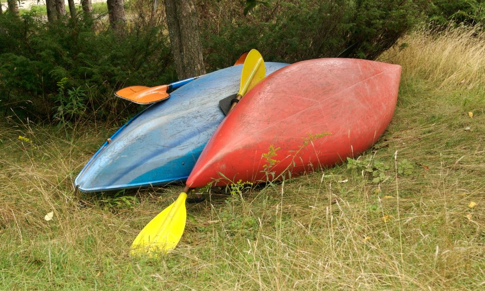 Used plastic kayaks lying upside down on grass showing hull condition – example for buying a used kayak inspection