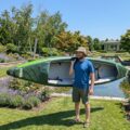Man carrying Odyssey Solo inflatable kayak by the lake showcasing portability and lightweight touring design